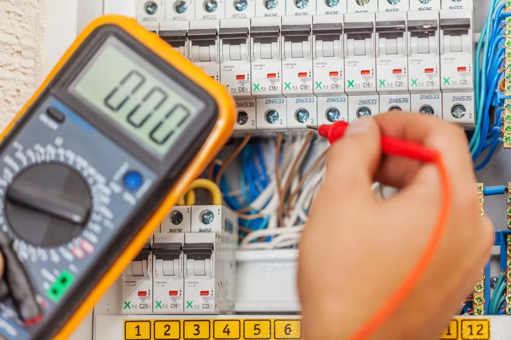 Electrician testing a consumer unit with a multimeter to find a fault